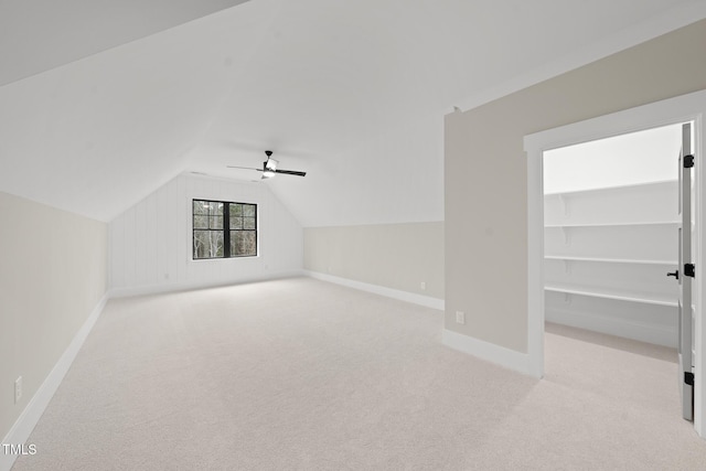 additional living space featuring vaulted ceiling, light carpet, a ceiling fan, and baseboards