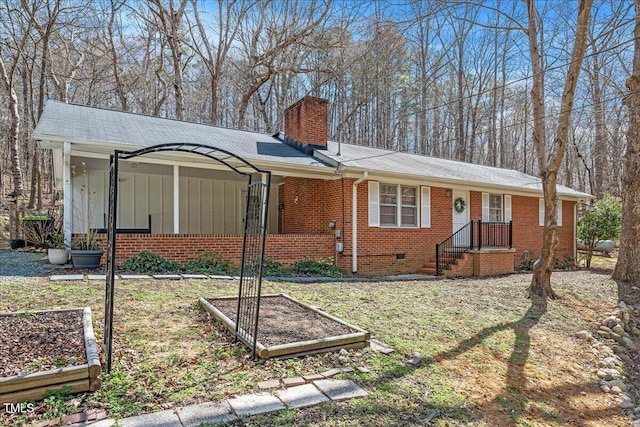 view of front of home featuring brick siding, a garden, crawl space, board and batten siding, and a chimney