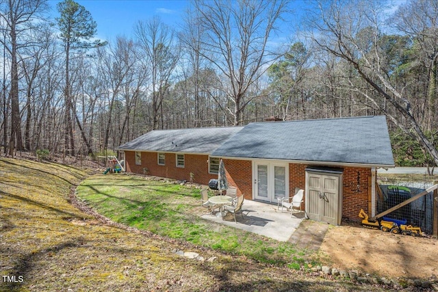 back of property with brick siding, a yard, and a patio