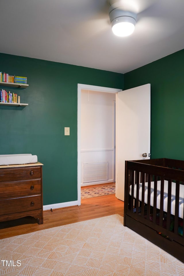 bedroom with wood finished floors, visible vents, and baseboards