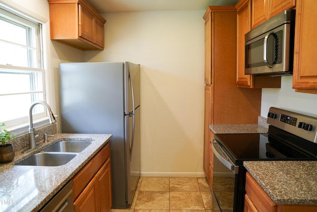 kitchen with brown cabinetry, a healthy amount of sunlight, appliances with stainless steel finishes, and a sink