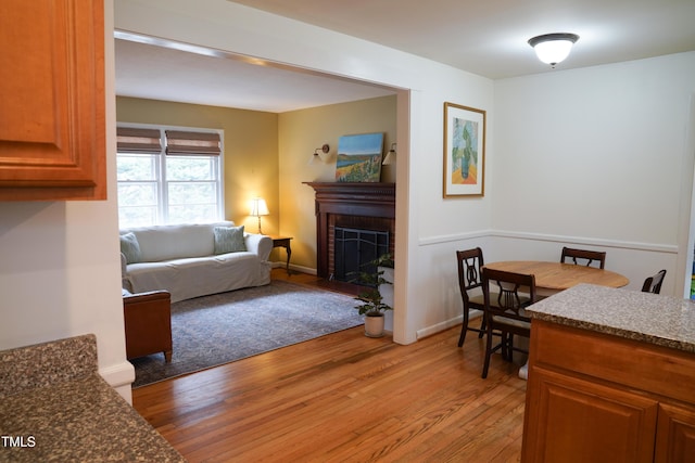 living room with a fireplace, baseboards, and light wood-style floors