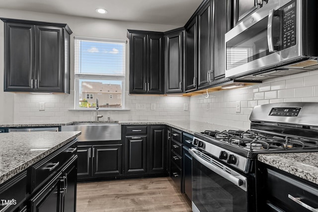 717 Tailrace Falls Ct, Wake Forest, NC 27587 - kitchen featuring appliances with stainless steel finishes, dark cabinetry, a sink, light wood-style flooring, and recessed lighting