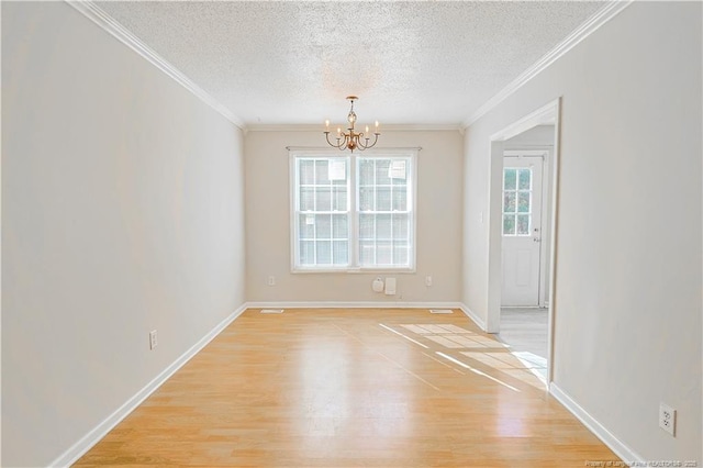 spare room featuring a chandelier, ornamental molding, a textured ceiling, and light wood-style flooring