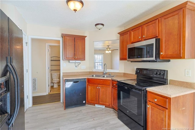 kitchen featuring a sink, visible vents, light countertops, light wood-type flooring, and black appliances