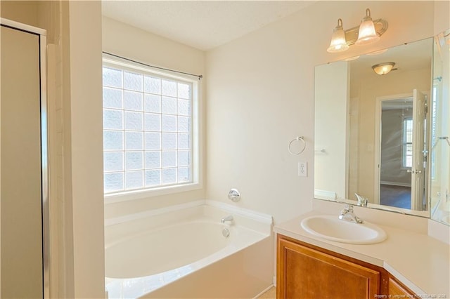 full bathroom with a healthy amount of sunlight, a garden tub, a textured ceiling, and vanity