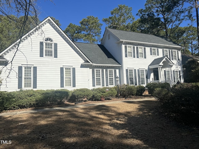 colonial inspired home with roof with shingles