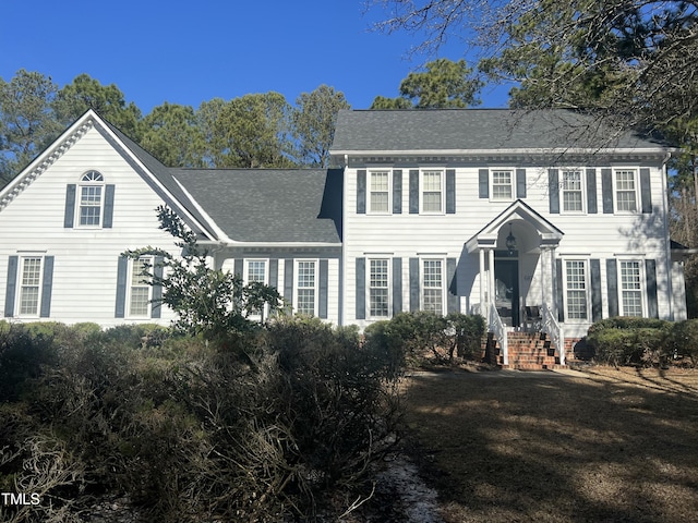 colonial-style house featuring roof with shingles