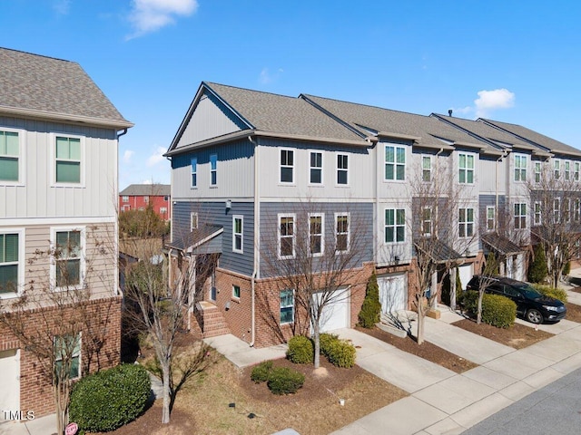 townhome / multi-family property with driveway, a garage, and brick siding