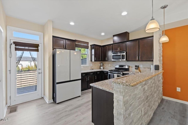 kitchen featuring light stone counters, stainless steel appliances, a peninsula, visible vents, and dark brown cabinets