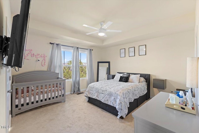 bedroom with ceiling fan, carpet floors, and a raised ceiling