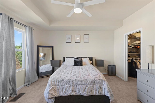 bedroom with light carpet, visible vents, baseboards, a closet, and a walk in closet