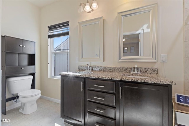 full bath with toilet, double vanity, baseboards, and a sink