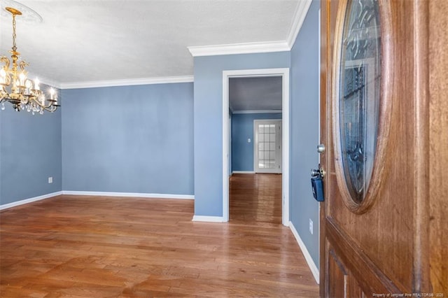 entryway with crown molding, baseboards, wood finished floors, and an inviting chandelier