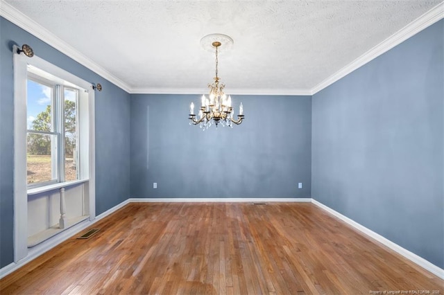 unfurnished room featuring an inviting chandelier, wood-type flooring, baseboards, and crown molding