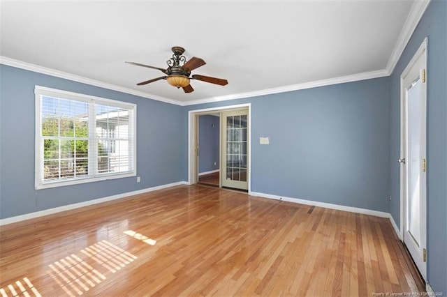 spare room featuring light wood-type flooring, crown molding, and baseboards