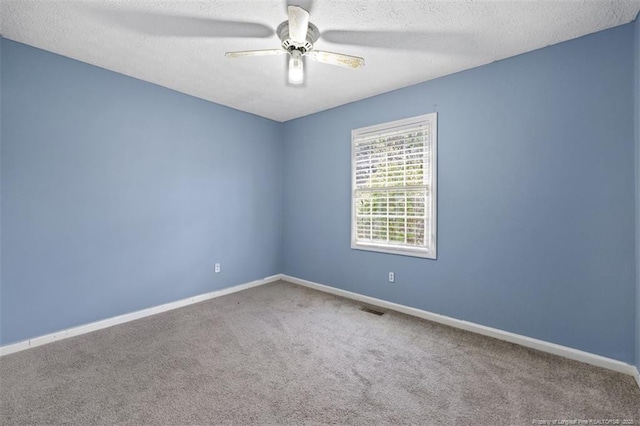 carpeted spare room with a ceiling fan, visible vents, a textured ceiling, and baseboards