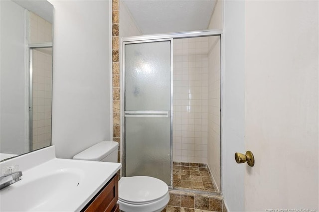 bathroom with a stall shower, vanity, and toilet