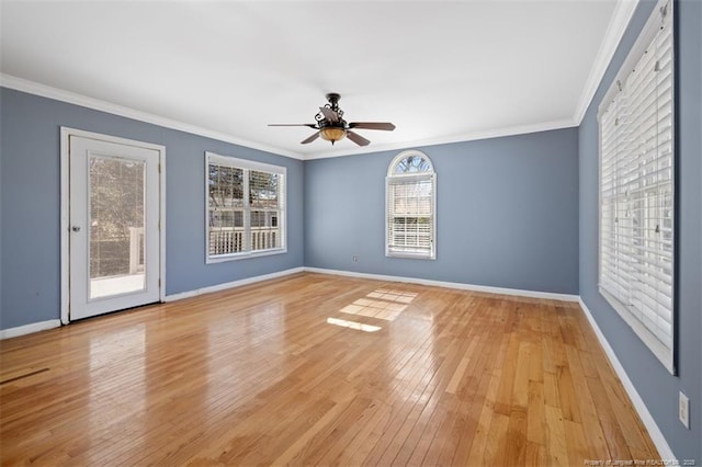 spare room with light wood-style floors, crown molding, baseboards, and a ceiling fan