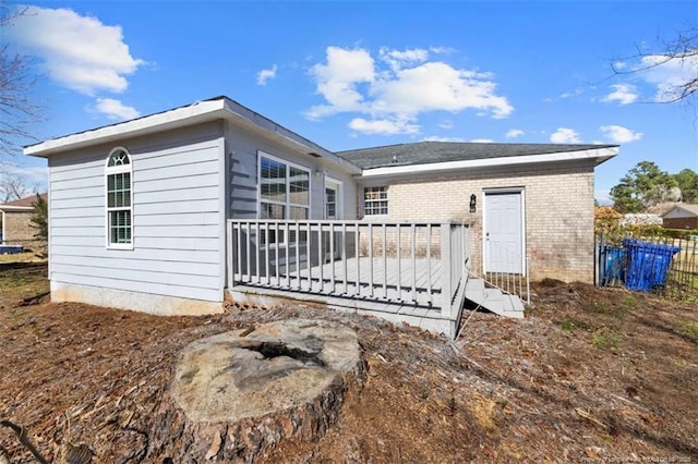 back of property with brick siding, fence, and a wooden deck