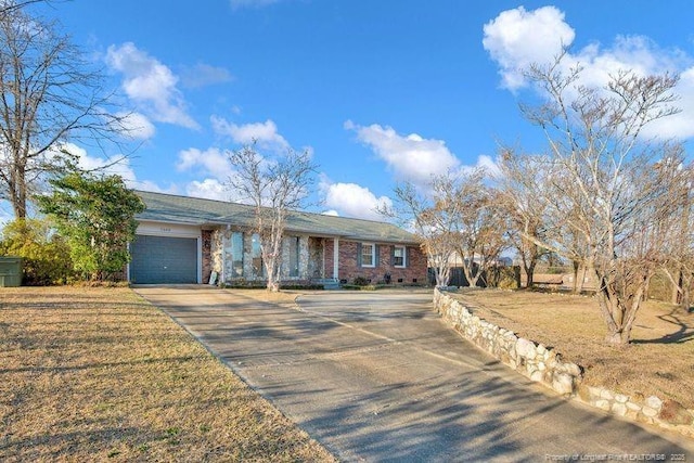 ranch-style home with driveway, an attached garage, and a front yard