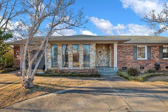 view of front facade with roof with shingles, brick siding, and crawl space