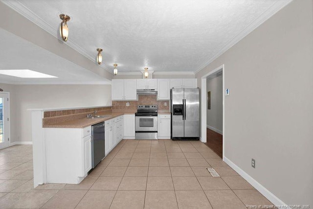 kitchen with a skylight, tasteful backsplash, appliances with stainless steel finishes, under cabinet range hood, and a sink