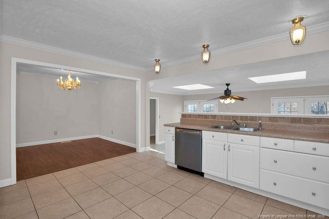 kitchen with a sink, a skylight, light tile patterned floors, and stainless steel dishwasher