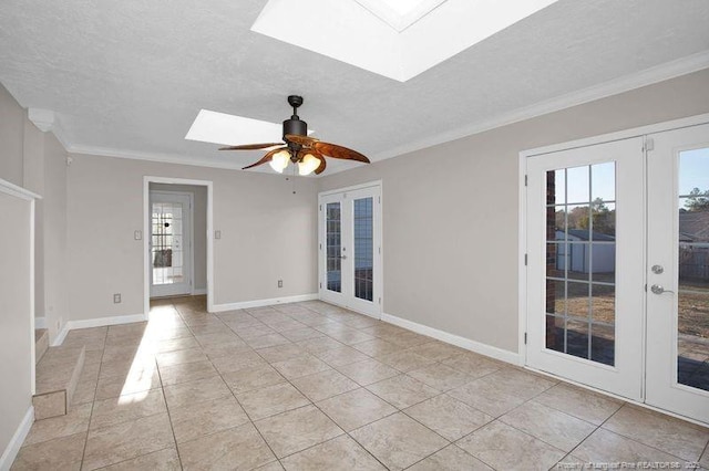 empty room with a skylight, crown molding, and french doors