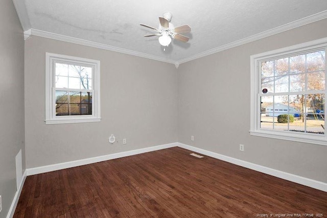 empty room with ornamental molding, wood finished floors, a ceiling fan, and baseboards