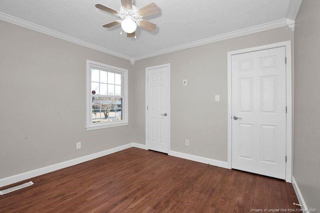 unfurnished bedroom featuring dark wood-style floors, ornamental molding, visible vents, and baseboards