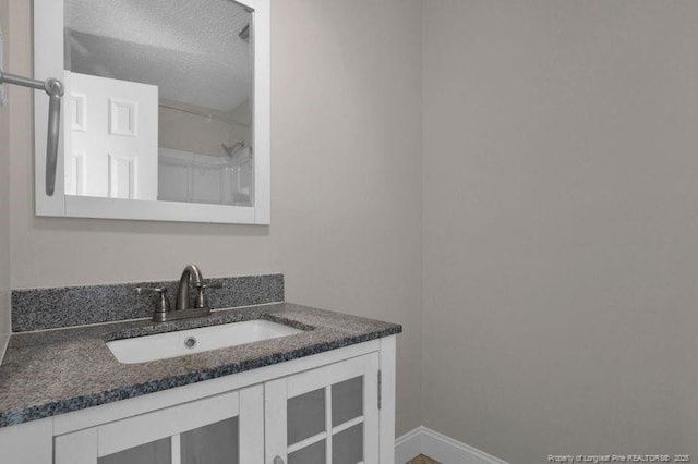 bathroom featuring baseboards, a textured ceiling, and vanity