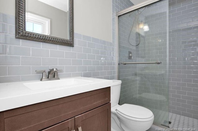 full bathroom featuring a stall shower, vanity, toilet, and tile walls