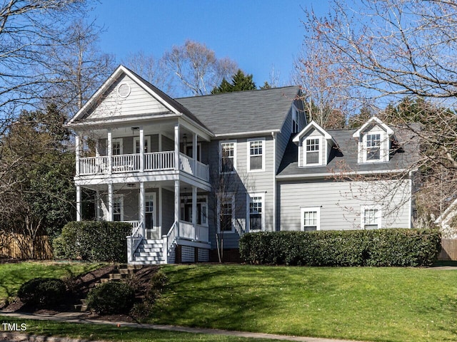 neoclassical home with a balcony, covered porch, and a front yard