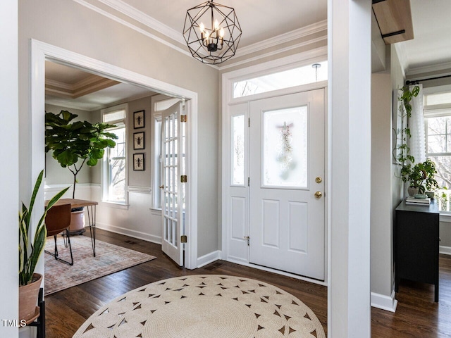 foyer entrance featuring a healthy amount of sunlight, ornamental molding, and dark wood finished floors