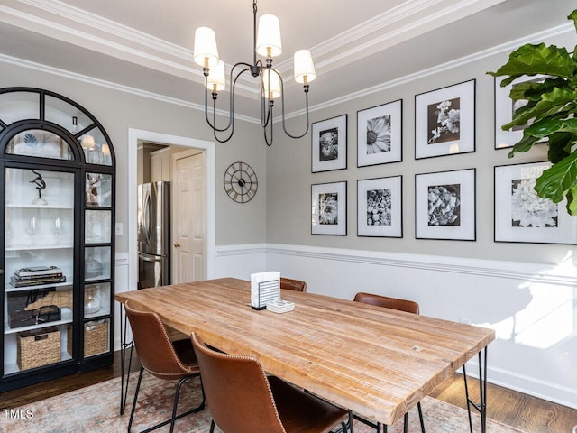 dining space with dark wood finished floors, a tray ceiling, crown molding, and a chandelier