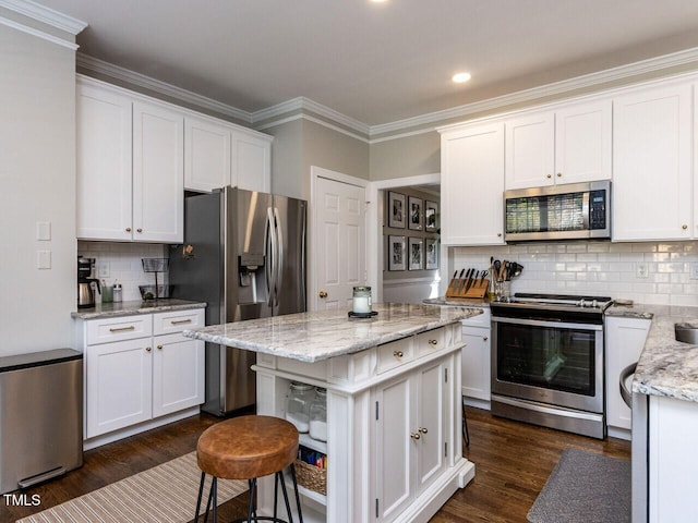 kitchen with dark wood-type flooring, tasteful backsplash, appliances with stainless steel finishes, white cabinets, and light stone countertops