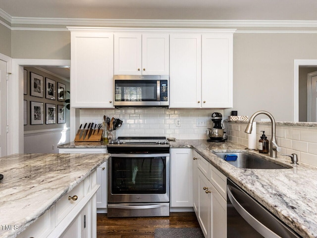 kitchen with a sink, crown molding, backsplash, and stainless steel appliances