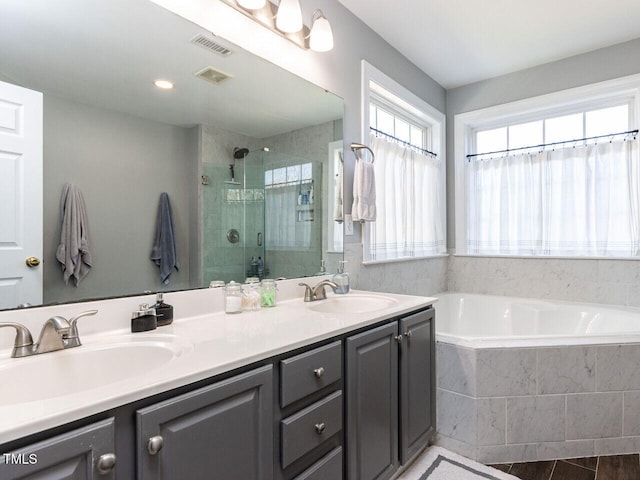 bathroom with visible vents, a stall shower, a garden tub, and a sink