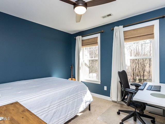 carpeted bedroom with visible vents, baseboards, and a ceiling fan