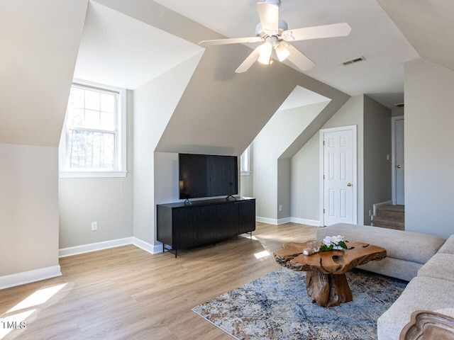 living room with vaulted ceiling, baseboards, visible vents, and light wood-type flooring