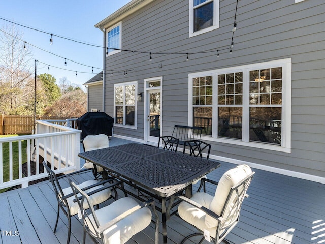 wooden deck with outdoor dining space, area for grilling, and fence