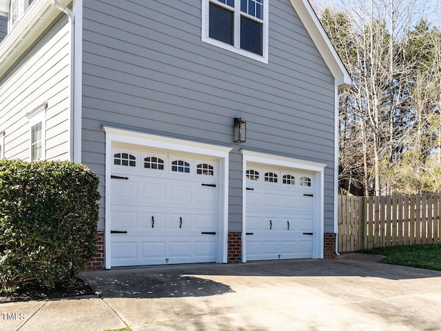 garage featuring driveway and fence