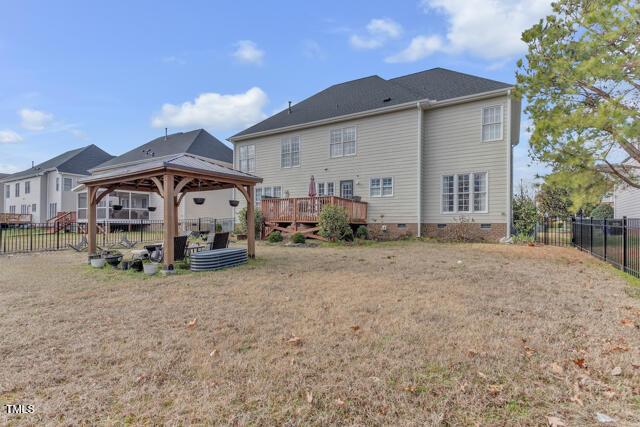 back of property featuring crawl space, a fenced backyard, a yard, and a gazebo