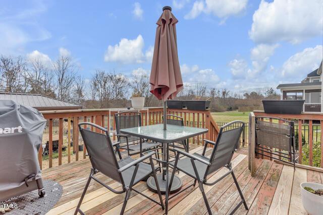 wooden deck featuring outdoor dining area and a grill