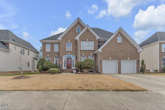 colonial home with brick siding, driveway, and an attached garage