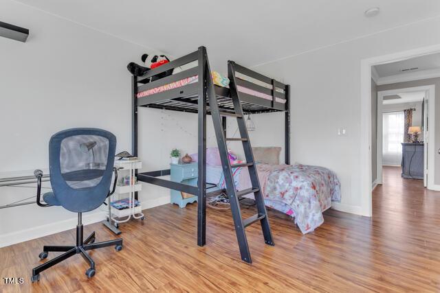 bedroom featuring ornamental molding, wood finished floors, and baseboards