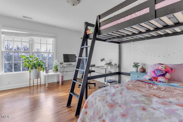 bedroom with wood finished floors, visible vents, and baseboards