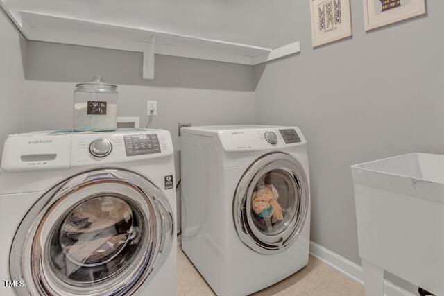 clothes washing area featuring baseboards, laundry area, a sink, and washer and dryer