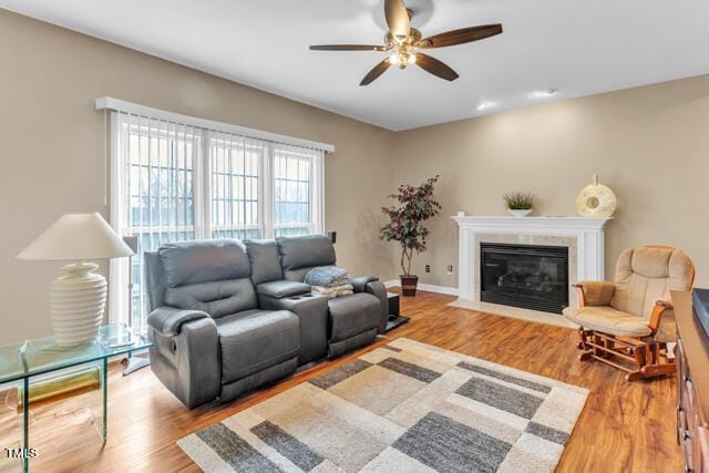 living room featuring a fireplace with flush hearth, wood finished floors, and a ceiling fan